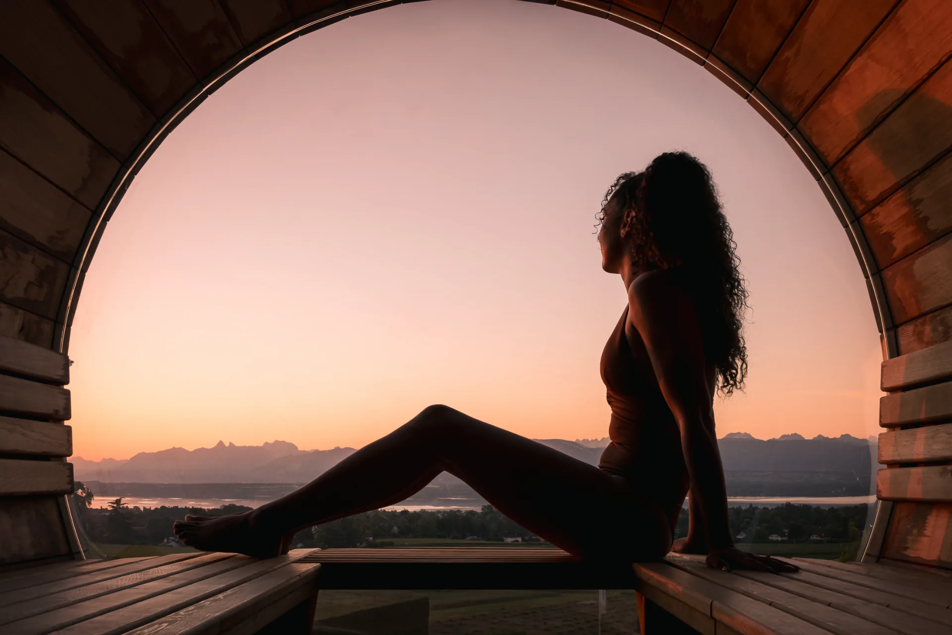 Silhouette dans un sauna barrique face aux Alpes au coucher du soleil