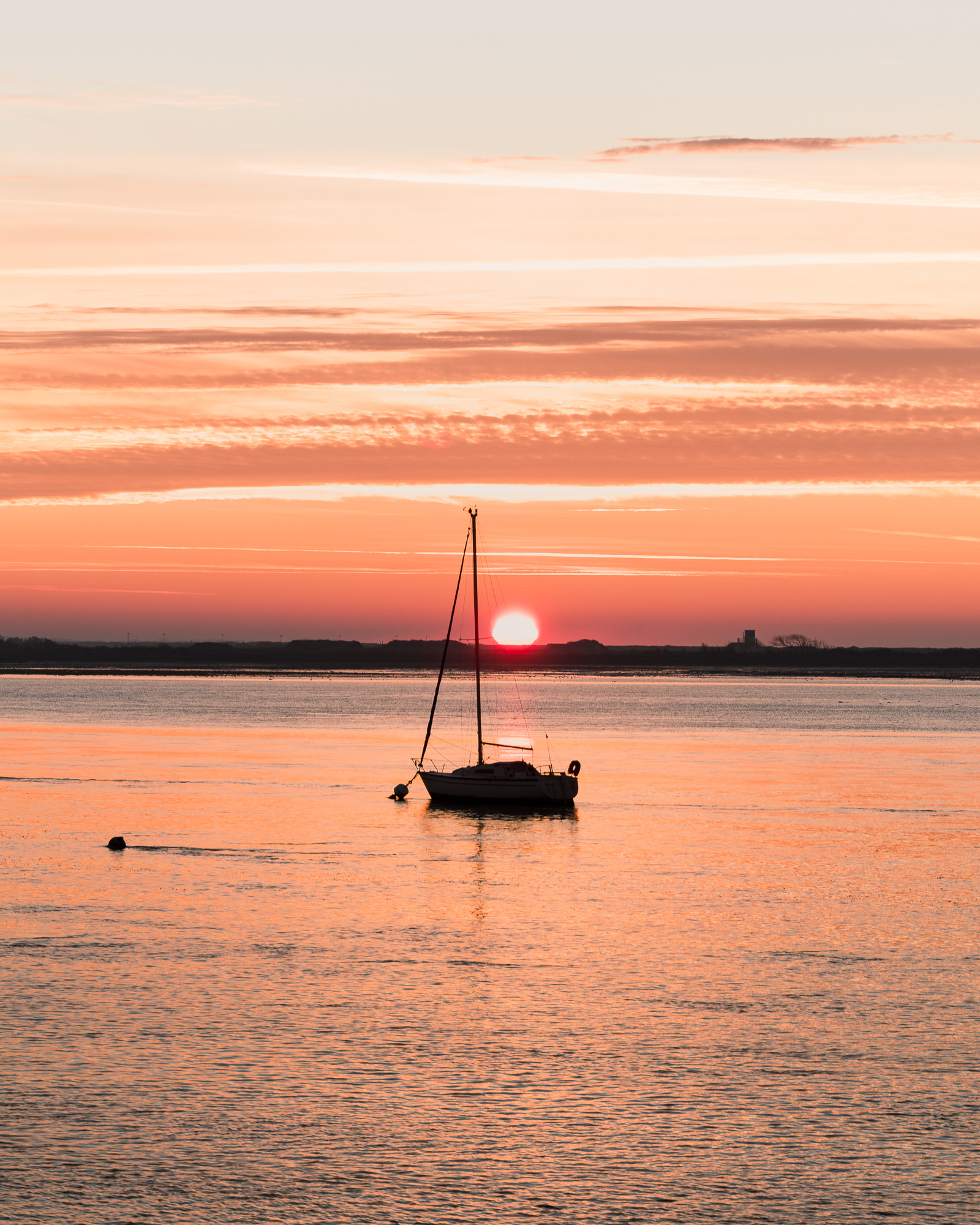 Voilier solitaire devant le soleil couchant sur la mer
